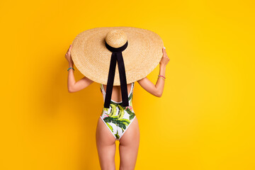 Photo of sexy slim lady wear swimsuit sun headwear standing back empty space isolated yellow color...