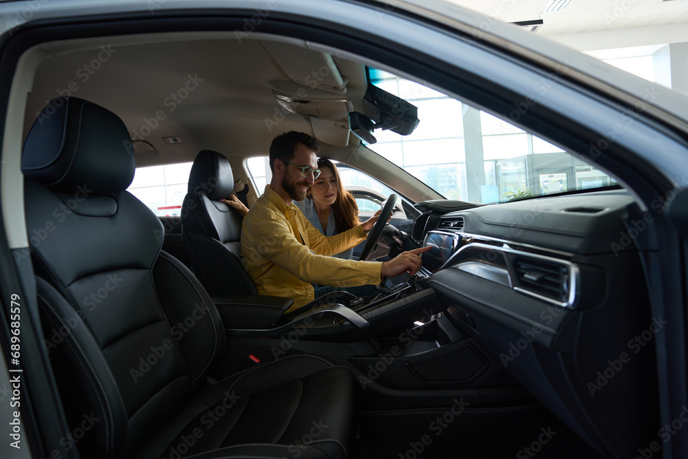 Wall mural young couple choosing auto in car showroom