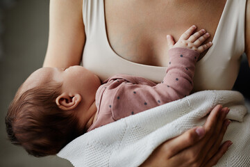 Side view at newborn napping in mothers arms, baby putting tiny hand on moms chest, copy space - obrazy, fototapety, plakaty