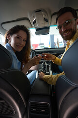 Happy couple posing at camera in car interior