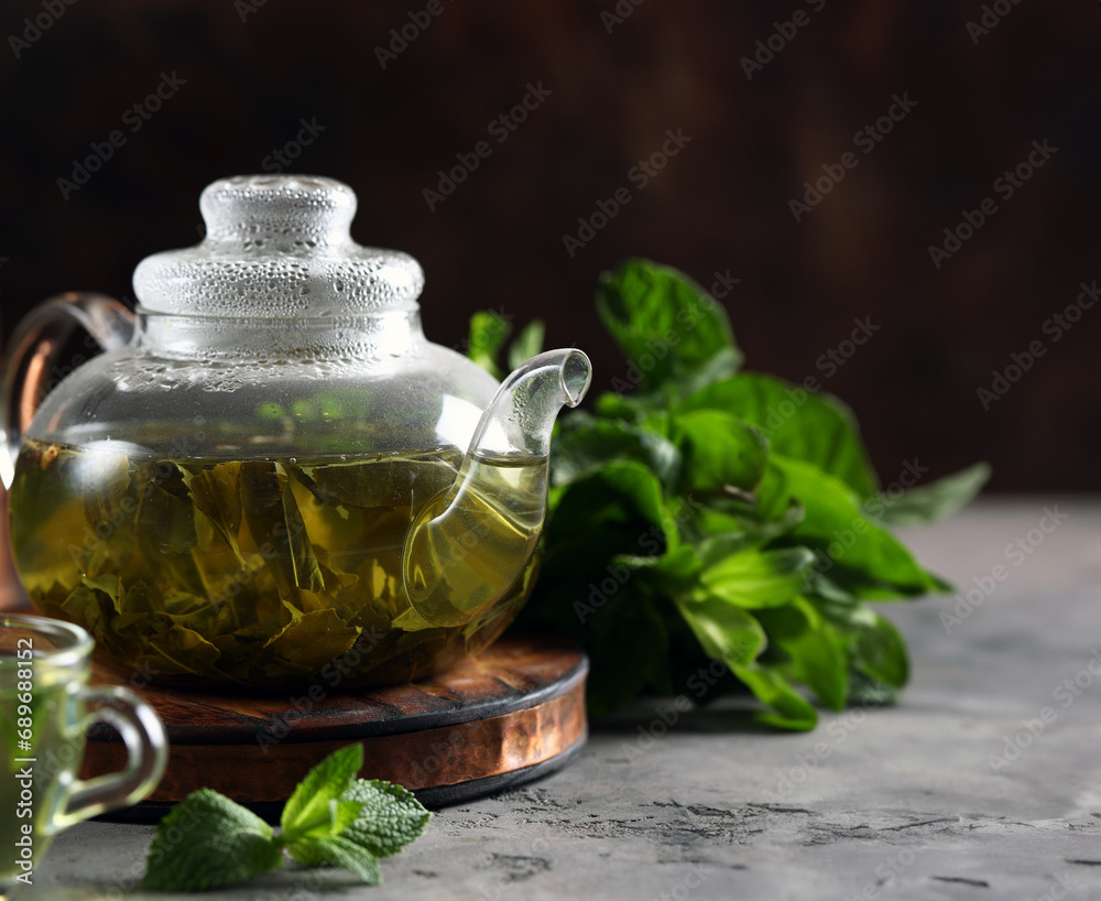 Sticker refreshing drink tea in a glass teapot on the table