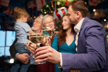 Women and men with boy clinking glasses celebrating Christmas in restaurant