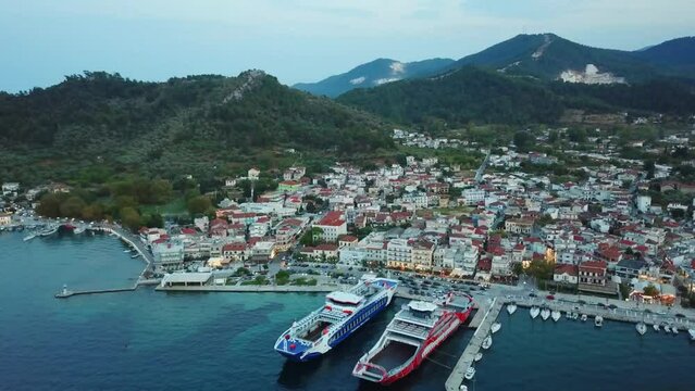 Limenas or Thassos City is the main city in Thassos Island , Greece , north-eastern Europe , aerial drone footage at sunset , showing the city , the harbor and the hills surrounding it.