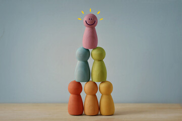 Human pyramid made of colorful wooden pawn - Concept of teamwork and diversity
