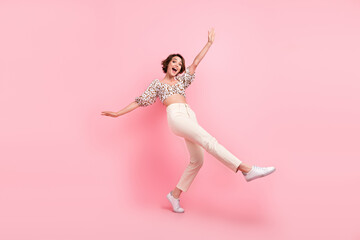 Fototapeta na wymiar Full size photo of good mood girl dressed stylish blouse white trousers stand on tiptoe hold balance isolated on pink color background
