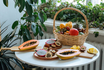 An assortment of fresh exotic fruits spread out on a table. Some fruits are cut and peeled. Some...