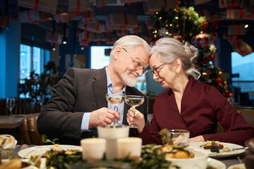 Happy aged man and woman with glasses of champagne celebrating New Year Eve