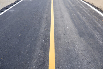 The yellow and white dividing line on the black asphalt road