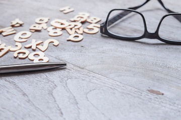 Empty wooden table with pen, eyeglasses, and wooden alphabets. Copy space for messages, text,...