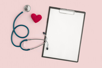 Medical stethoscope for checking pulse on a pink background with a red heart, with a tablet for...