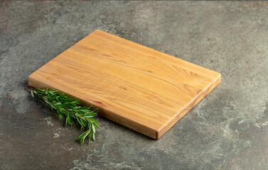 Cutting board and rosemary on a stone table.