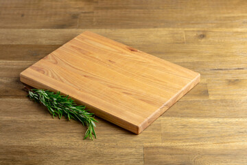 Cutting board and rosemary on an old wooden table.
