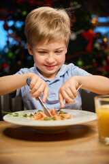 Little boy having festive dinner in restaurant during Christmas celebration