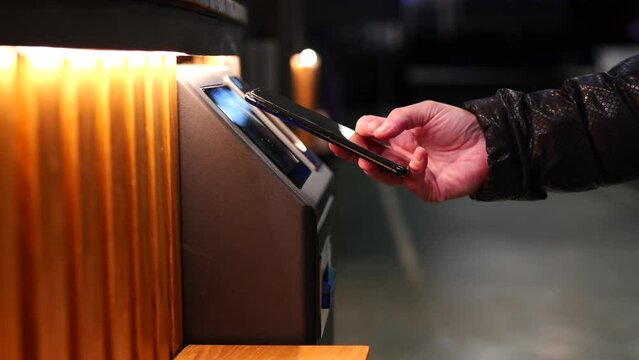 woman paying with her smart phone at an ATM machine