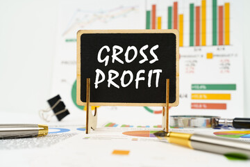 Against the background of business graphs, a board with the inscription - gross profit