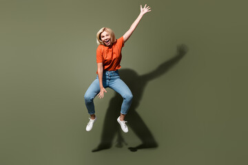 Full size body photo of cool girl riding air jumping carefree hand raised up wear casual outfit isolated on khaki color background