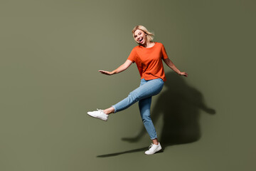 Fototapeta na wymiar Full length photo of lovely young lady crazy dancing clubber have fun wear trendy orange garment isolated on khaki color background