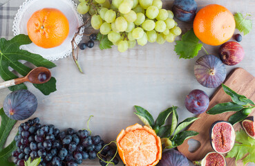 Fresh orange tangerine, figs and grape fruit mix with green leaves on gray wooden table with copy space, healthy food background