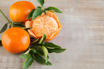 Orange tangerine fruit with green leaves on brown wood with copy space, healthy food background