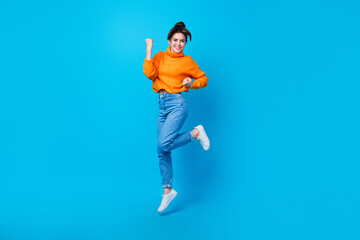 Full length photo of funky lucky lady wear knitted pullover jumping high rising fist isolated blue color background