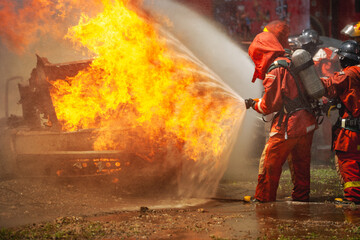 firefighter training fireman team use extinguish spraying fire car. Fire fighter learning stop fire burn under emergency case at fire station. rescue service of Emergency Care System of Insurance team