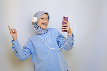 cheerful muslim asian woman in blue shirt listening music on headphone