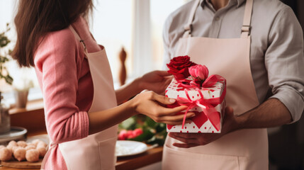 Couple in love in the kitchen exchanges homemade gifts in honor of Valentine's Day. A man and a...