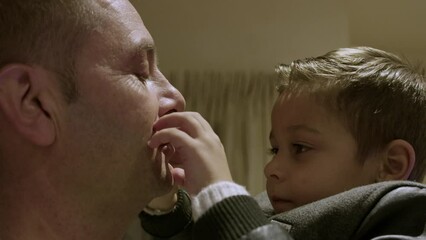 Cute preschool boy kissing his dad and closing his lips with hands. Happy family, bonding and quality family time. High quality 4k footage