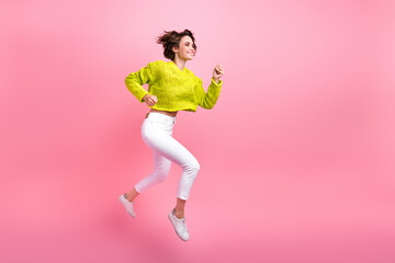 Full length photo of cute charming girl dressed neon sweater jumping high running fast empty space...