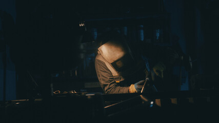 A man works with a welding machine at a factory