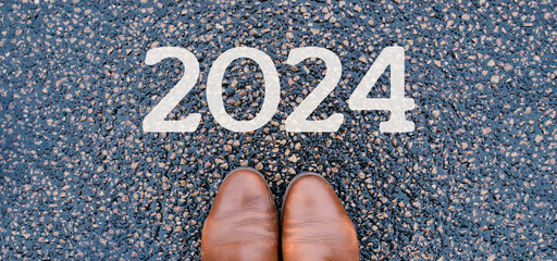 New year 2024 is standing on the road, feet in shoes on ground calendar date, end of the year,...