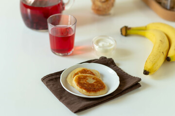 Pancakes on a white plate with banana and berry juice