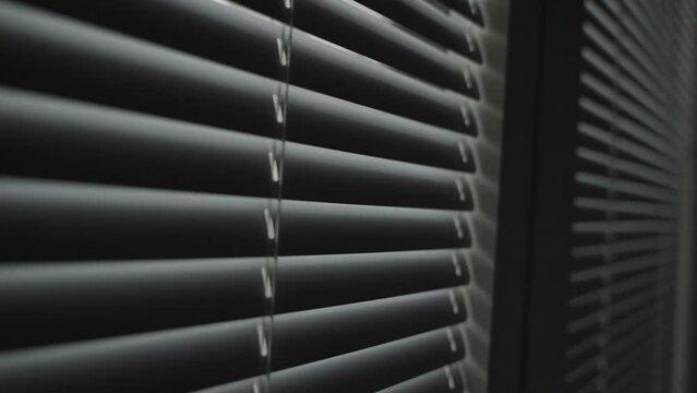 Window venetian blinds or shades close in close up shot from inside house room. Mysterious room or office indoors with window shutters being shut or lowered to make room dark without light inside
