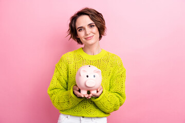 Photo of young girl collect in pig bank earn coins for future studying in european expensive...