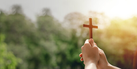 girl holding a cross to pray thank god Praise the Lord with outdoor background, pray, easter and good holidays concept - obrazy, fototapety, plakaty