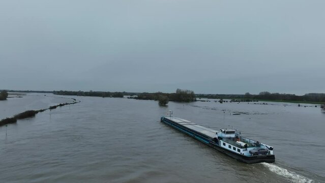Ship on the river IJssel with high water level on the floodplains near the city of Zwolle in Overijssel during summer after heavy rainfall upstream. Aerial drone point of view.