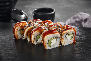 A delectable Canada maki roll with succulent eel and rich unagi sauce, sprinkled with sesame seeds, presented on a black slate