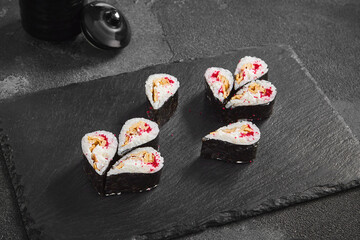 Droplet sushi roll featuring a fluffy Japanese omelet and tobiko caviar, tastefully arranged on a dark slate serving board