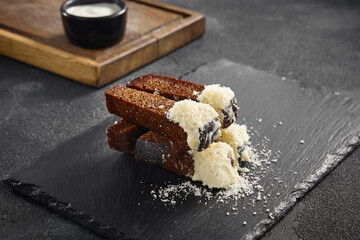 Savory garlic croutons stacked with a sprinkle of cheese, accompanied by a creamy cheese sauce on a slate plate.