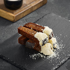 Savory garlic croutons stacked with a sprinkle of cheese, accompanied by a creamy cheese sauce on a slate plate