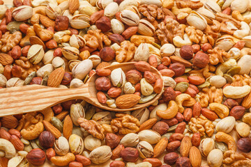 Nuts and seeds of different types with a wooden spoon closeup with selective focus - peeled walnut,...