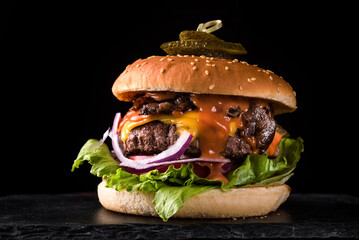 Beef burger on black stone board on black background.