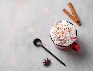 Red mug with hot chocolate or cocoa with whipped cream, with spoon, cinnamon sticks and star anise