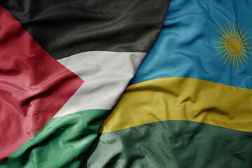 big waving national colorful flag of rwanda and national flag of palestine .