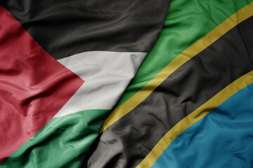 big waving national colorful flag of tanzania and national flag of palestine .