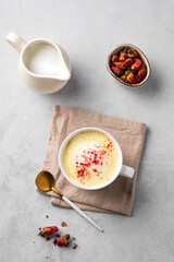 Flat lay of a golden milk latte with turmeric and rose petals. Trendy Indian drink Moon milk with natural spices.