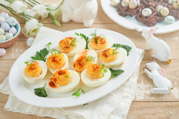 Easter stuffed eggs. Traditional Easter brunch or dinner with stuffed eggs with paprika, carrot cake bars and chocolate nest cakes with glazed eggs. Easter meal dishes with holday decorations Top view