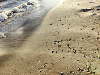Yellow sand, pebbles and a transparent wave as a background, texture. Abstract pattern, place for text, copy space