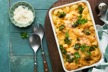 Pasta Broccoli casserole. Baked Mac and cheese with broccoli, cream sauce and parmesan on old rustic wooden background. Healthy or baby food. American Casserole Top view. Copy space.