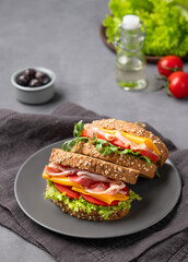 Club sandwich on a plate with a bacon, cheese, tomato and lettuce on a dark background